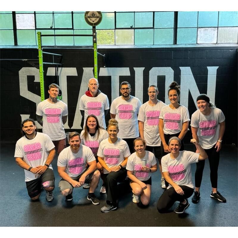 A group of people posing for a picture in front of a sign that says station