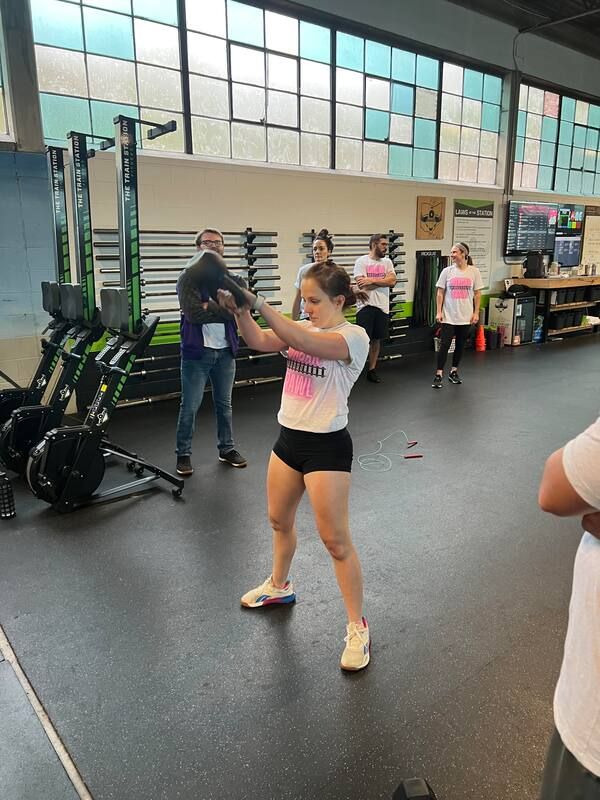 A woman is standing in a gym holding a barbell.