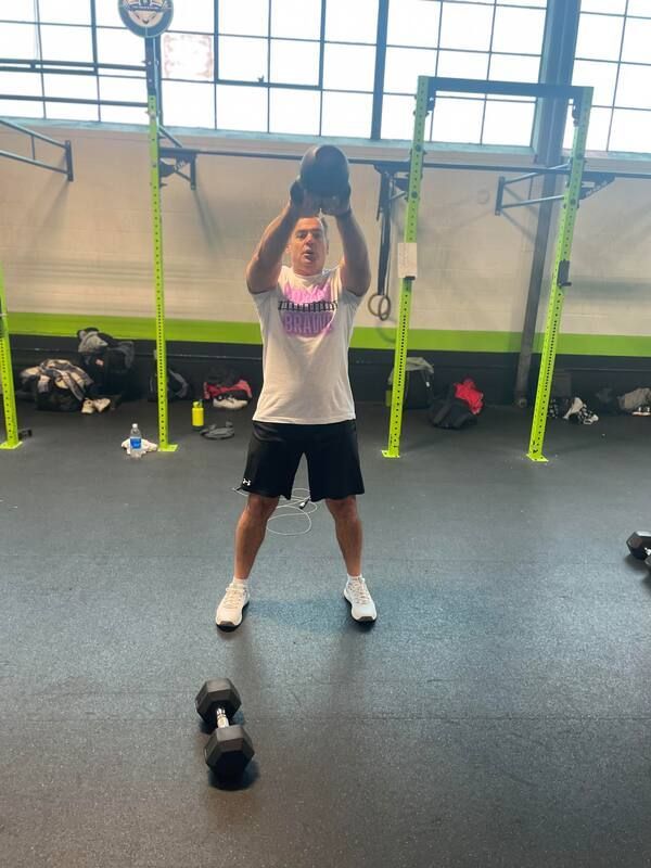 A man is lifting a dumbbell in a gym