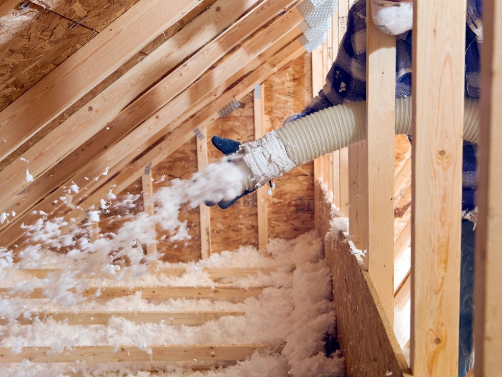 A person is blowing insulation into the attic of a house under construction.