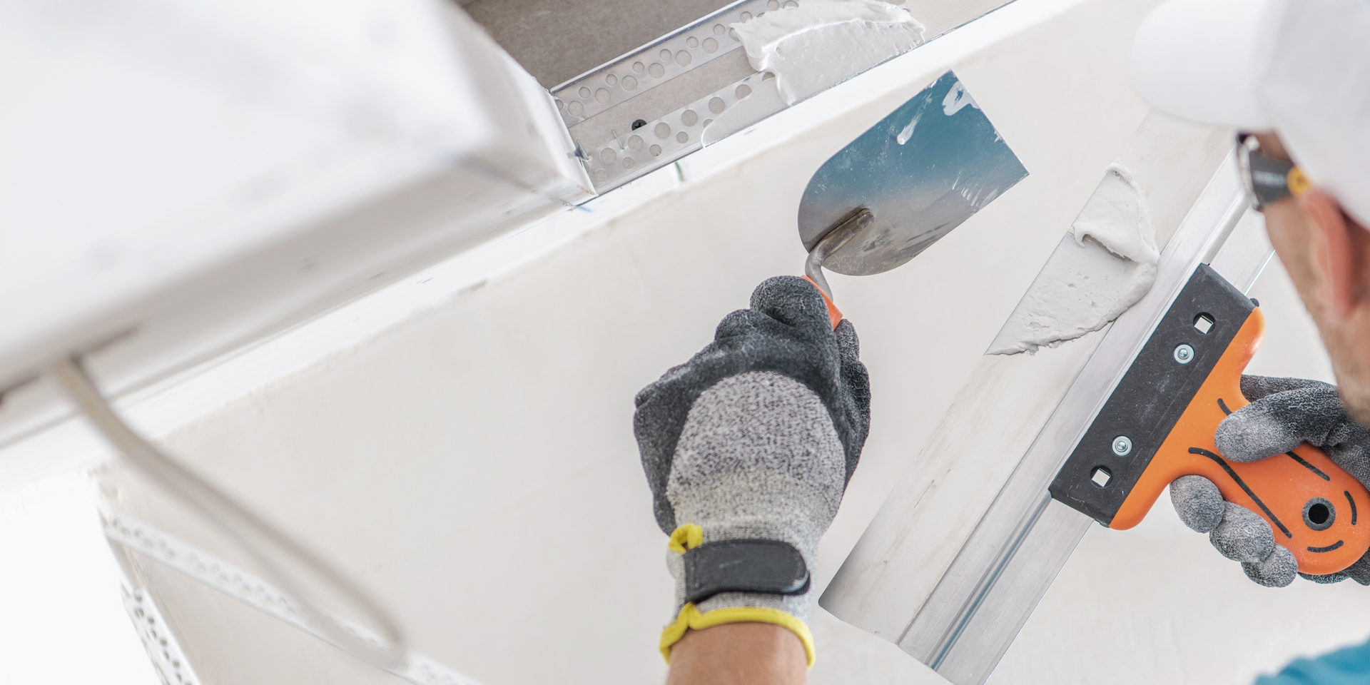 Person using a putty knife to apply plaster to a ceiling.