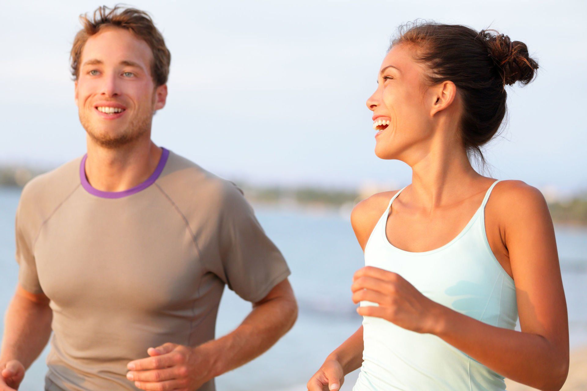 A man and a woman are jogging on the beach