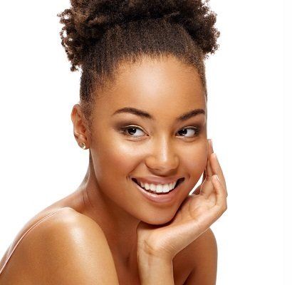A woman with curly hair is smiling with her hand on her face