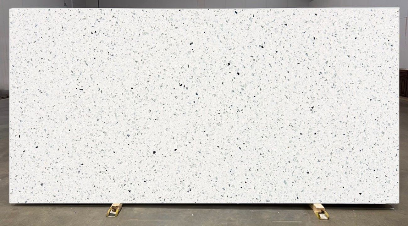 Large white speckled stone slab displayed upright on small supports outdoors.