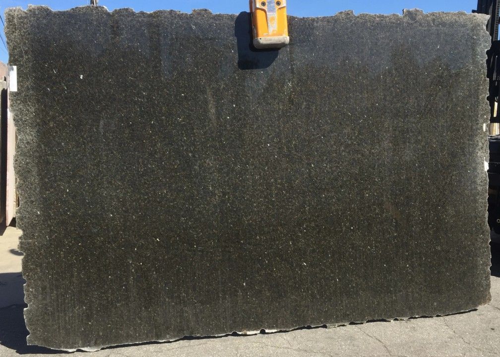 Large dark textured rectangular panel leaning outdoors on a concrete surface, with a small orange clip at the top center