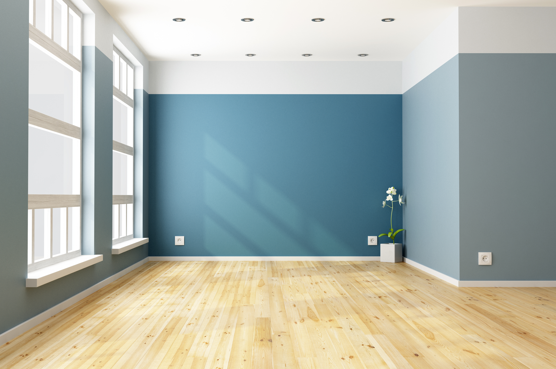Empty room with light wood floors, blue and white walls, and large windows.