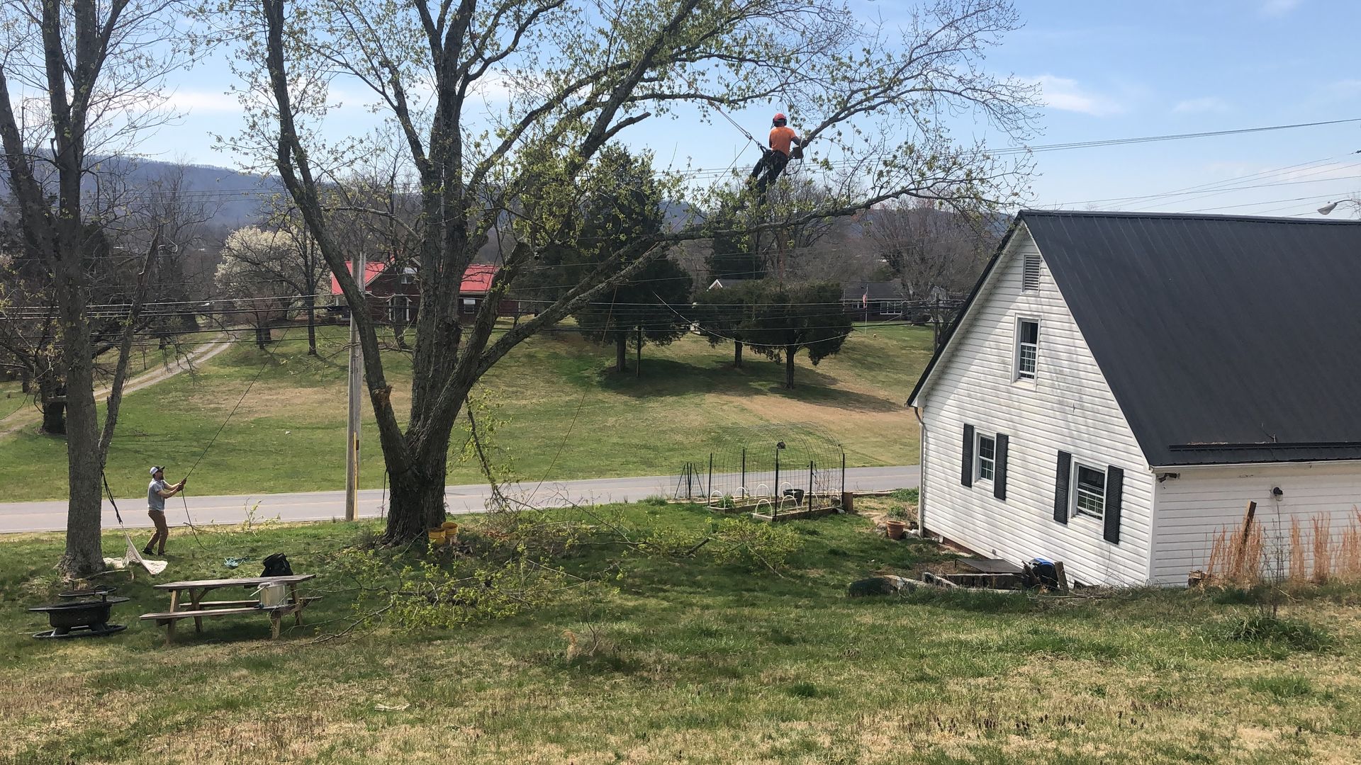 A white house with a black roof is sitting in the middle of a grassy field.