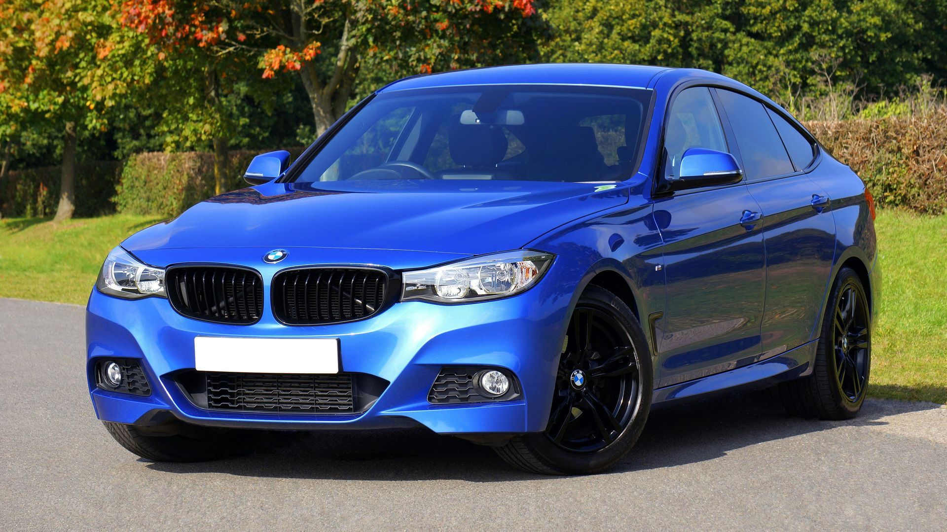 A blue bmw 3 series is parked on the side of the road.