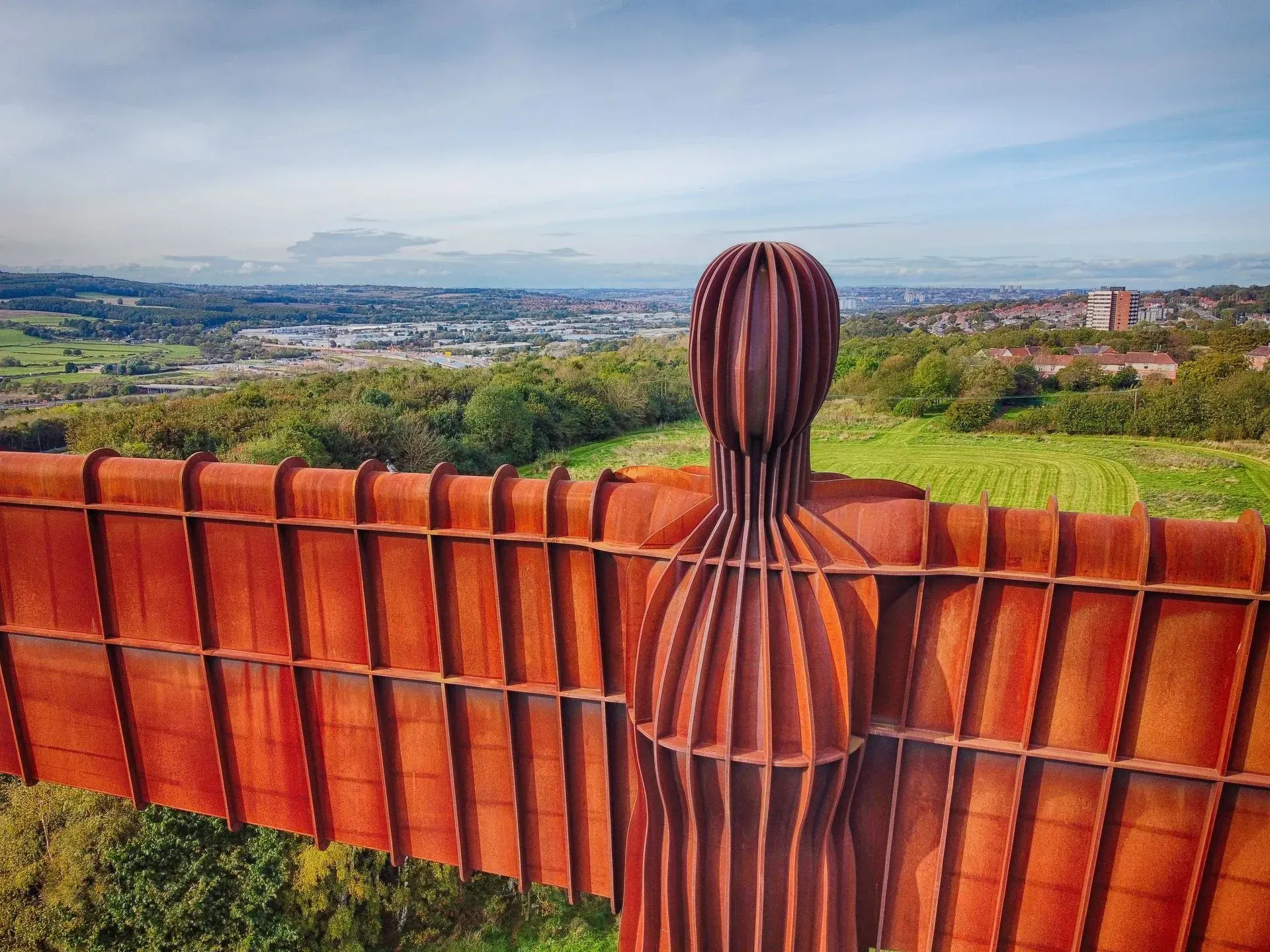 A statue of a woman with wings is standing on top of a fence overlooking a city.
