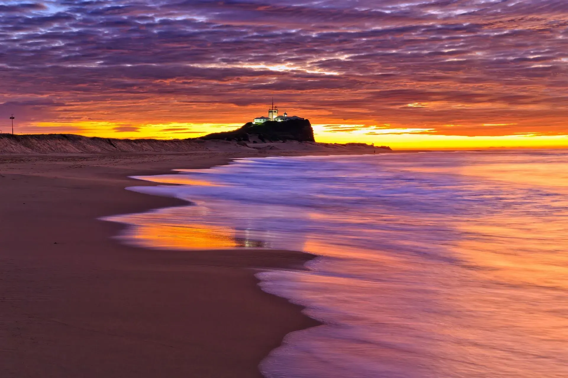A beach at sunset with a mountain in the background