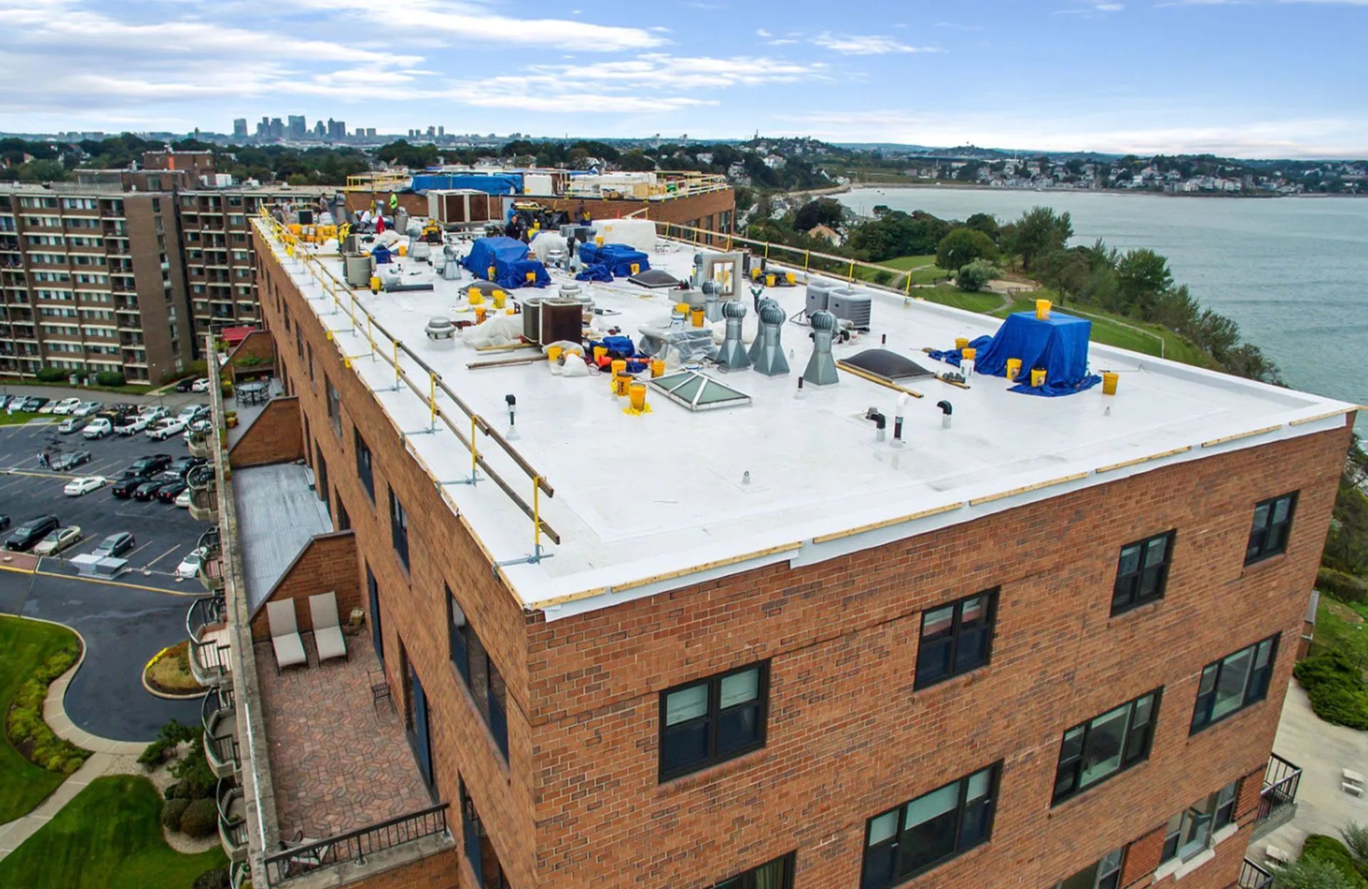 Brick building with flat roof; rooftop equipment, waterfront view, overcast sky.