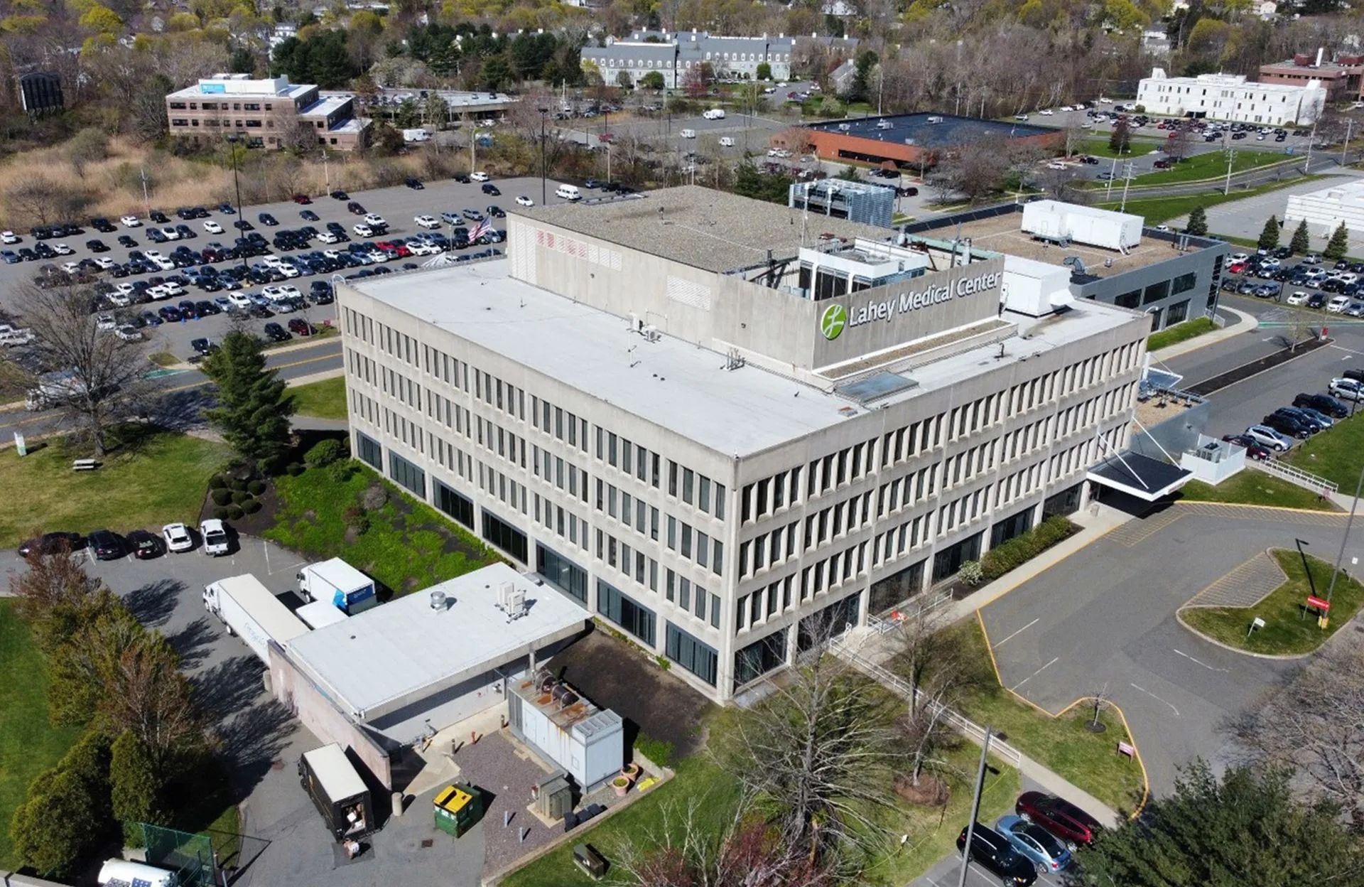Aerial view of a multi-story office building with a large parking lot on a sunny day.