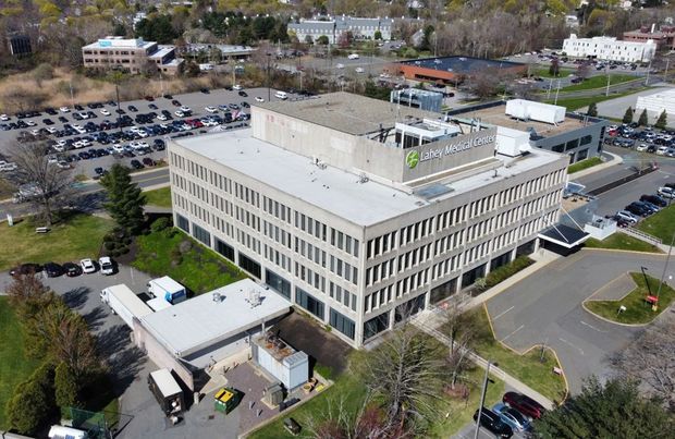 Aerial view of a multi-story office building with a large parking lot on a sunny day.