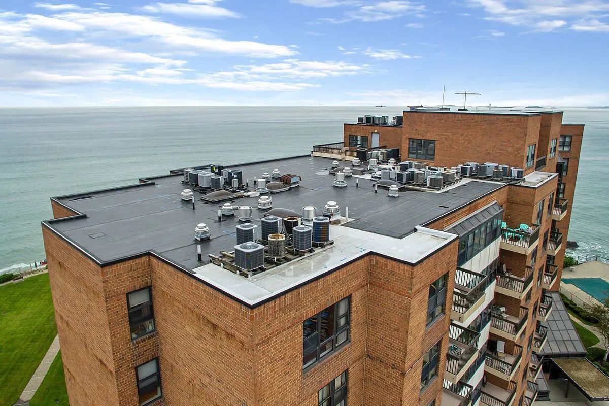 Brick building rooftop with HVAC units, near ocean.