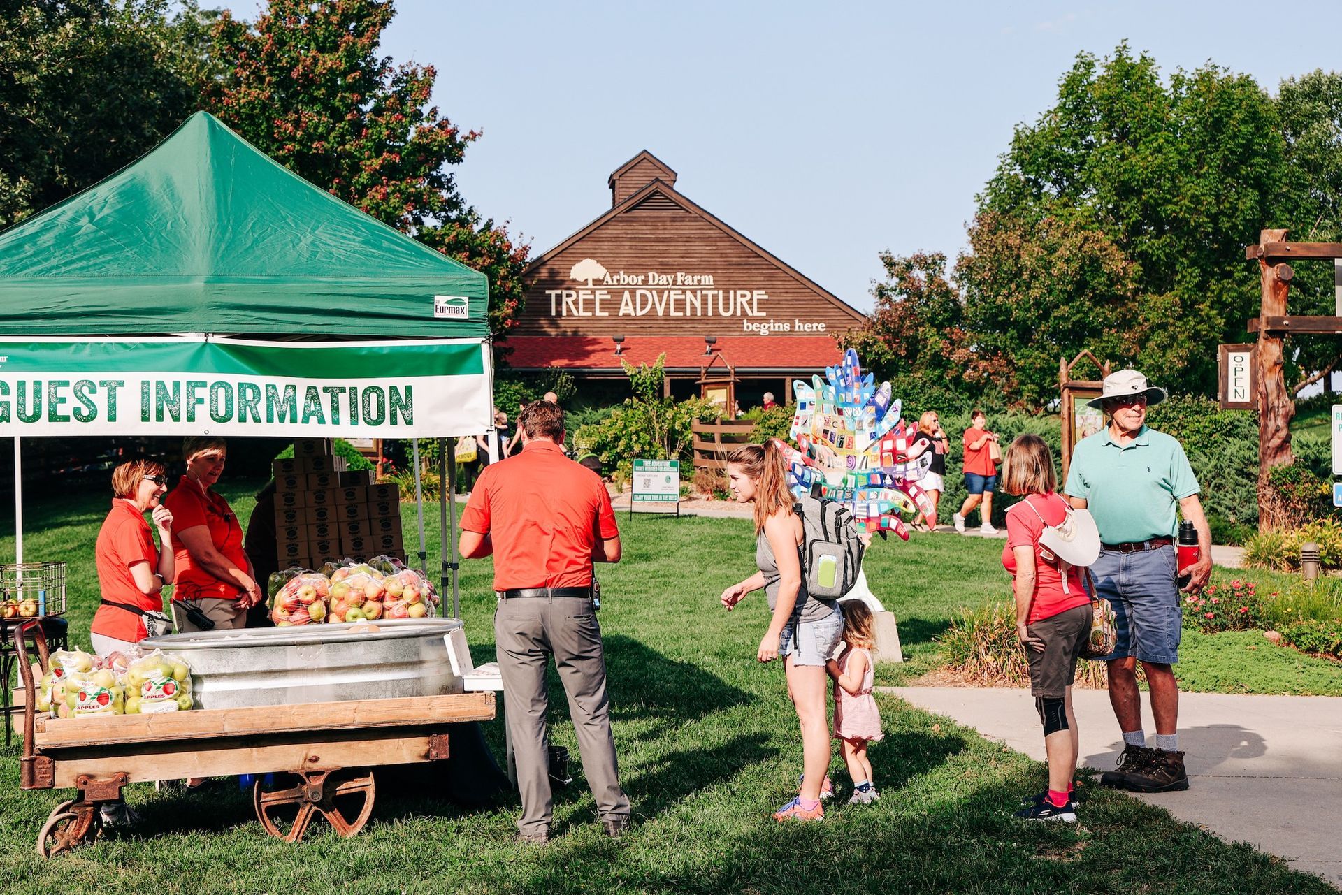 A group of people are standing in front of a tent that says guest information.