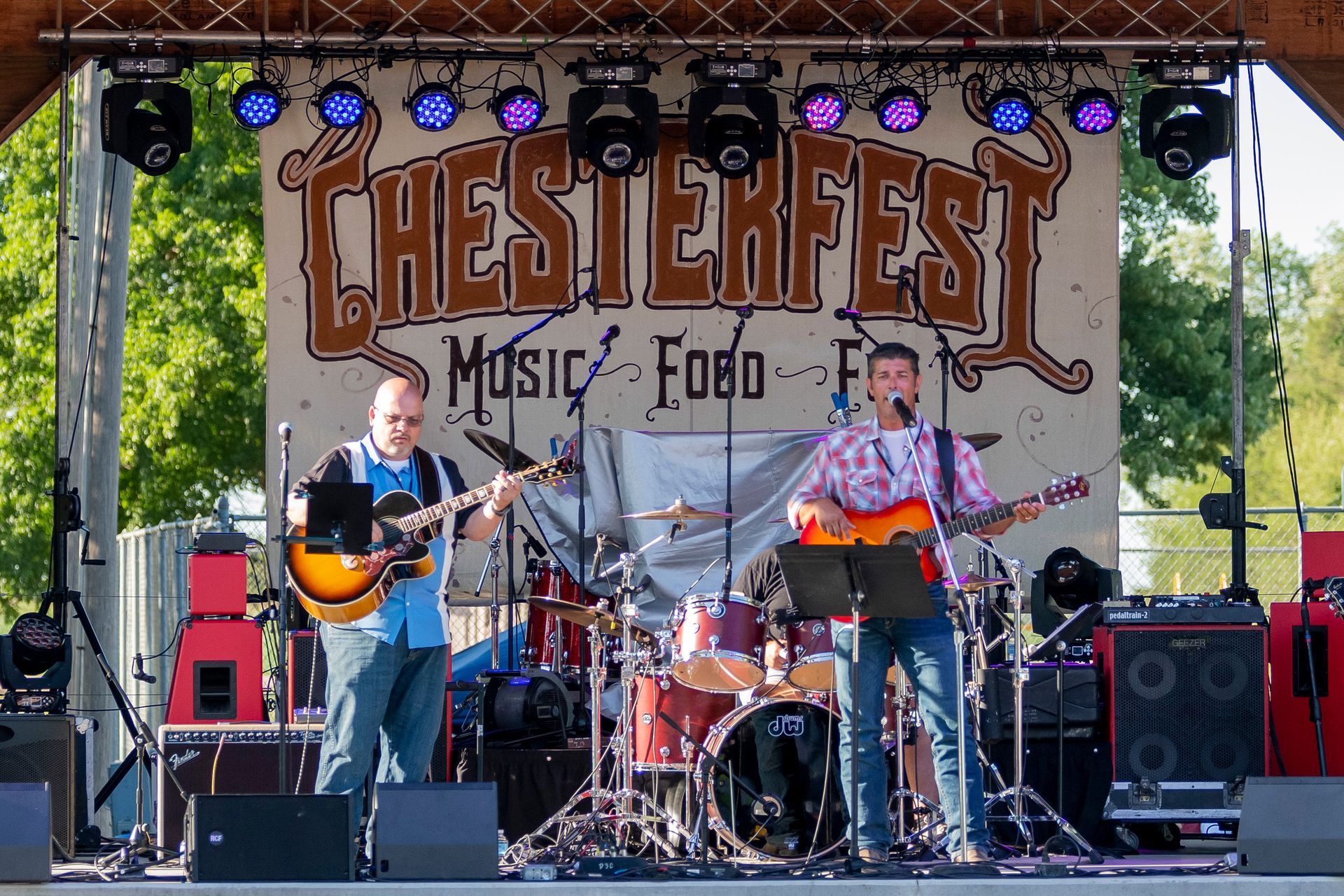 Two men are playing guitars on a stage at chesterfest