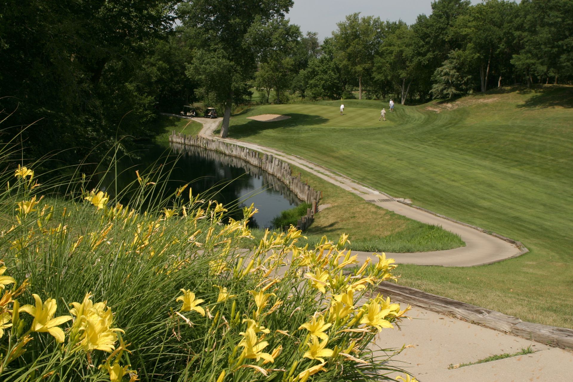 A golf course with a bridge and flowers in the foreground