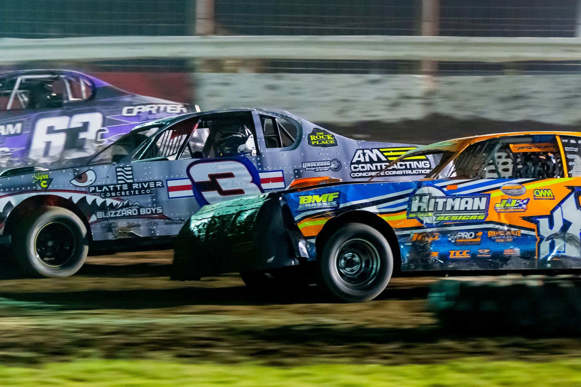 Two race cars are racing on a dirt track.