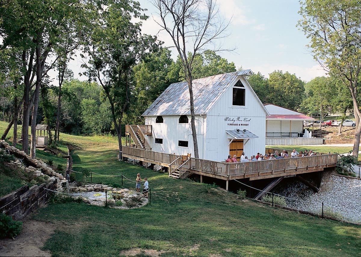 A white barn with a wooden bridge in front of it