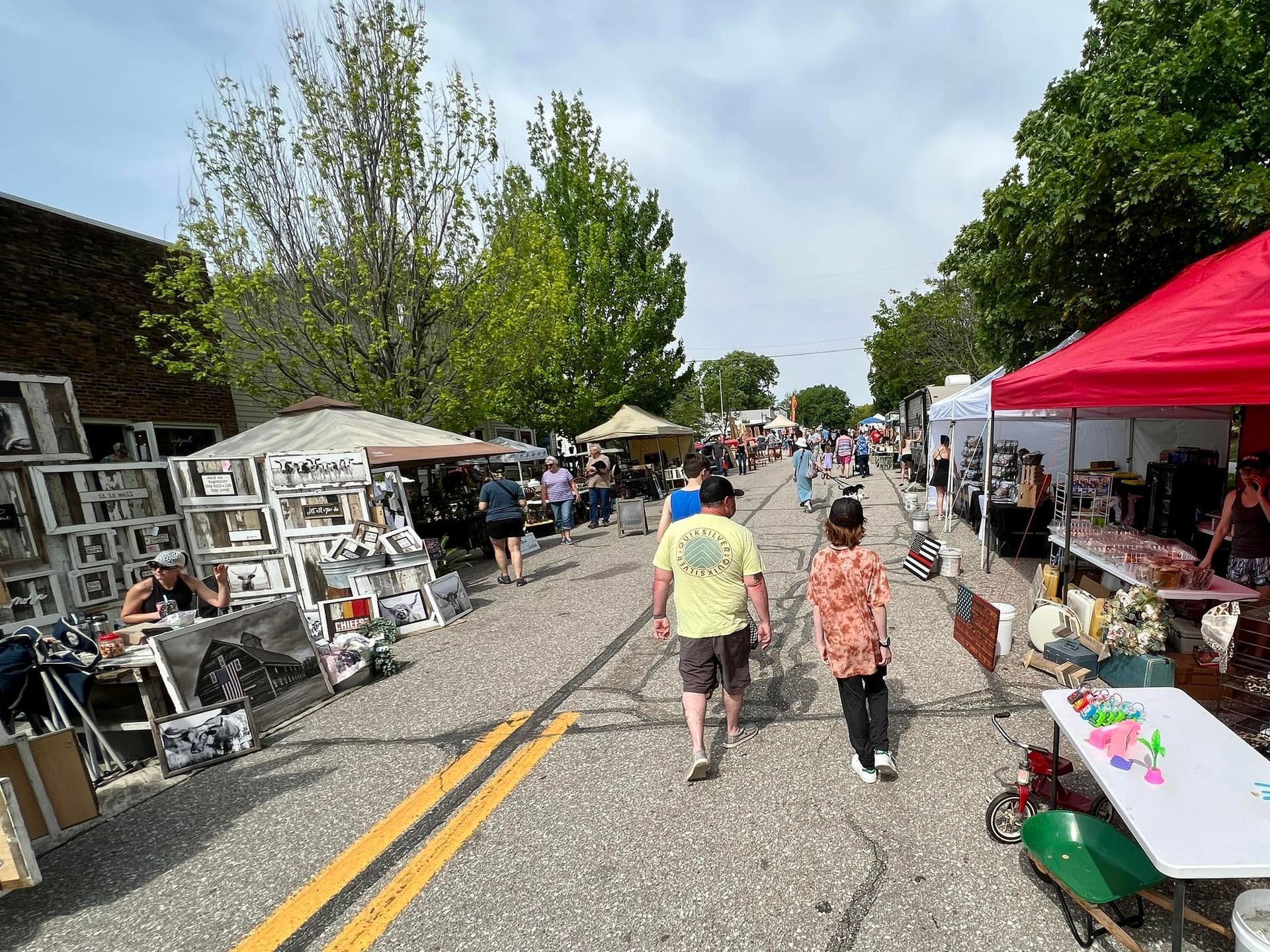 A group of people are walking down a street filled with lots of vendors.