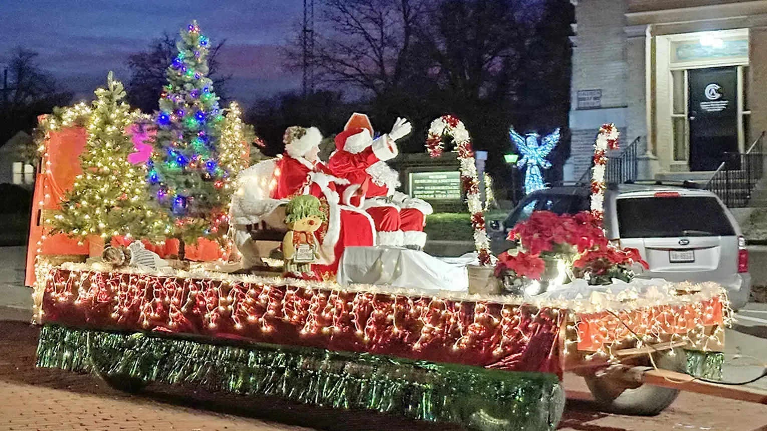 A christmas parade float decorated with santa claus and christmas trees.