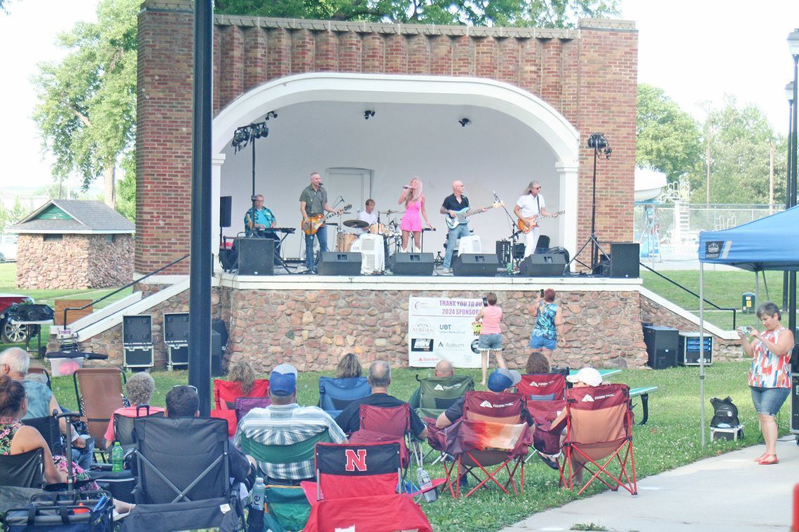 A group of people are sitting in front of a stage watching a band perform.