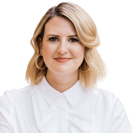 A woman with blonde hair is wearing a white shirt and earrings.