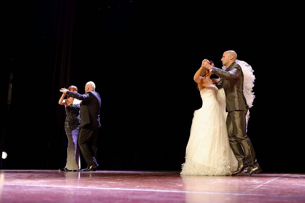 Une mariée et un marié dansent sur une scène avec des anges.
