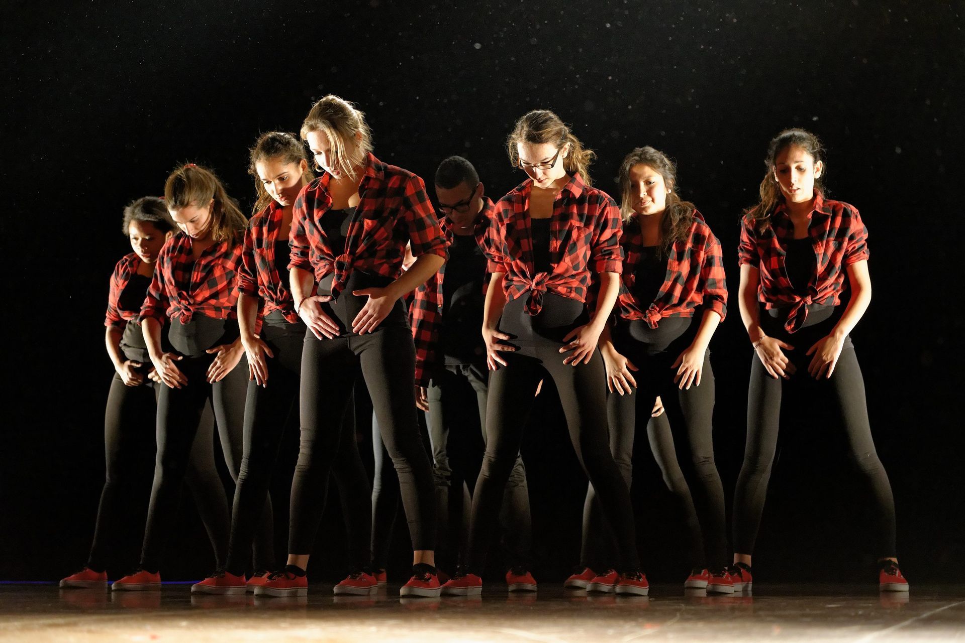 Un groupe de danseurs se tient en rang sur une scène.