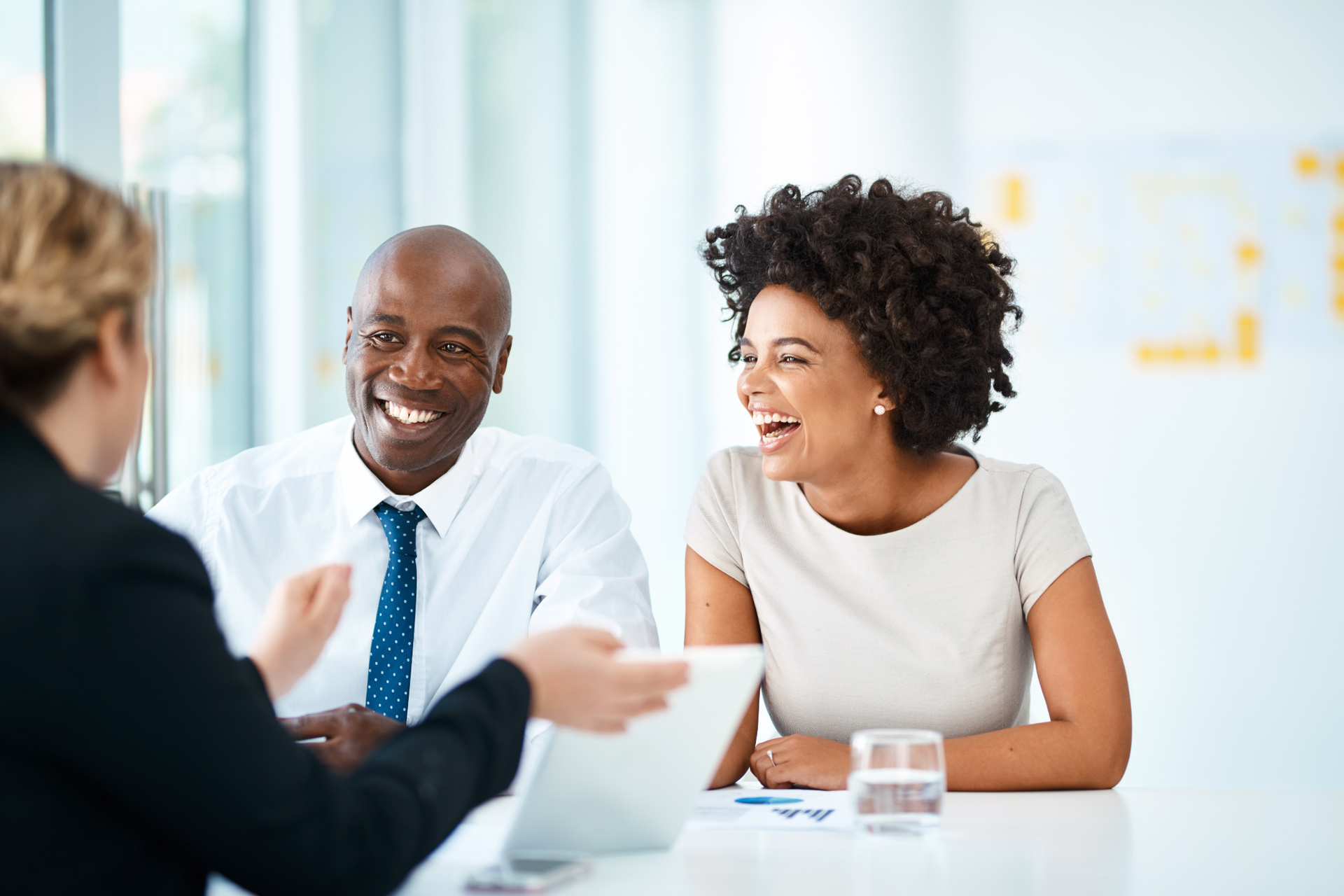 Four young adults walking and talking together down a city sidewalk, sunny day.