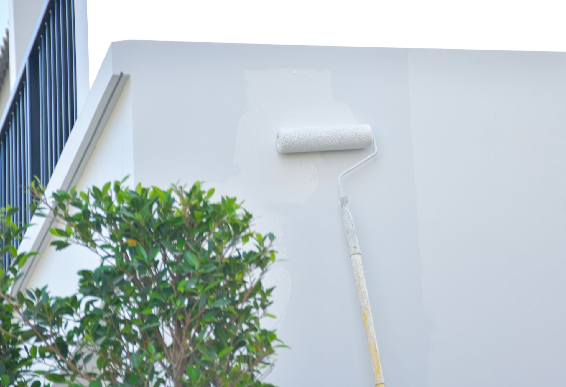 A person is painting a white wall with a roller.