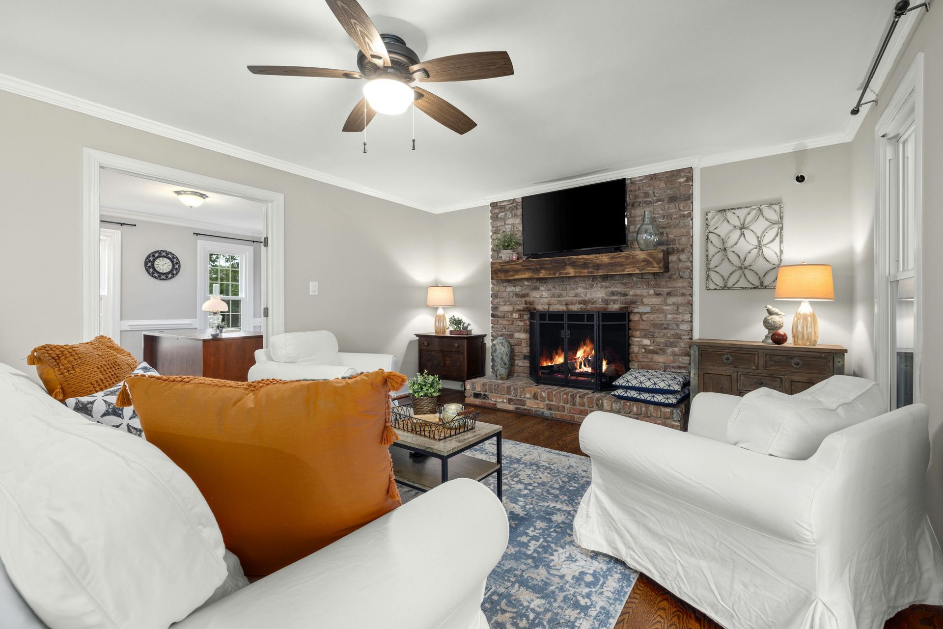 A living room with a fireplace and a ceiling fan.