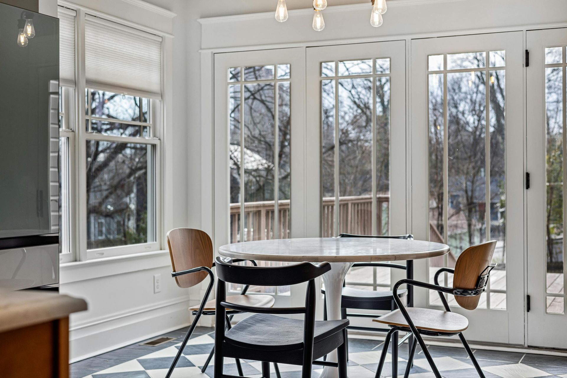 A dining room with a table and chairs and a lot of windows.