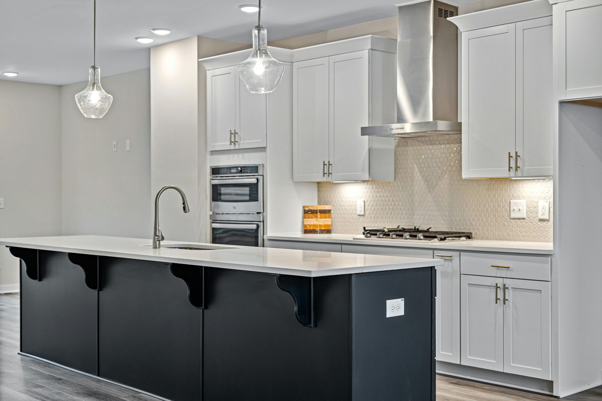 A kitchen with white cabinets and a black island.