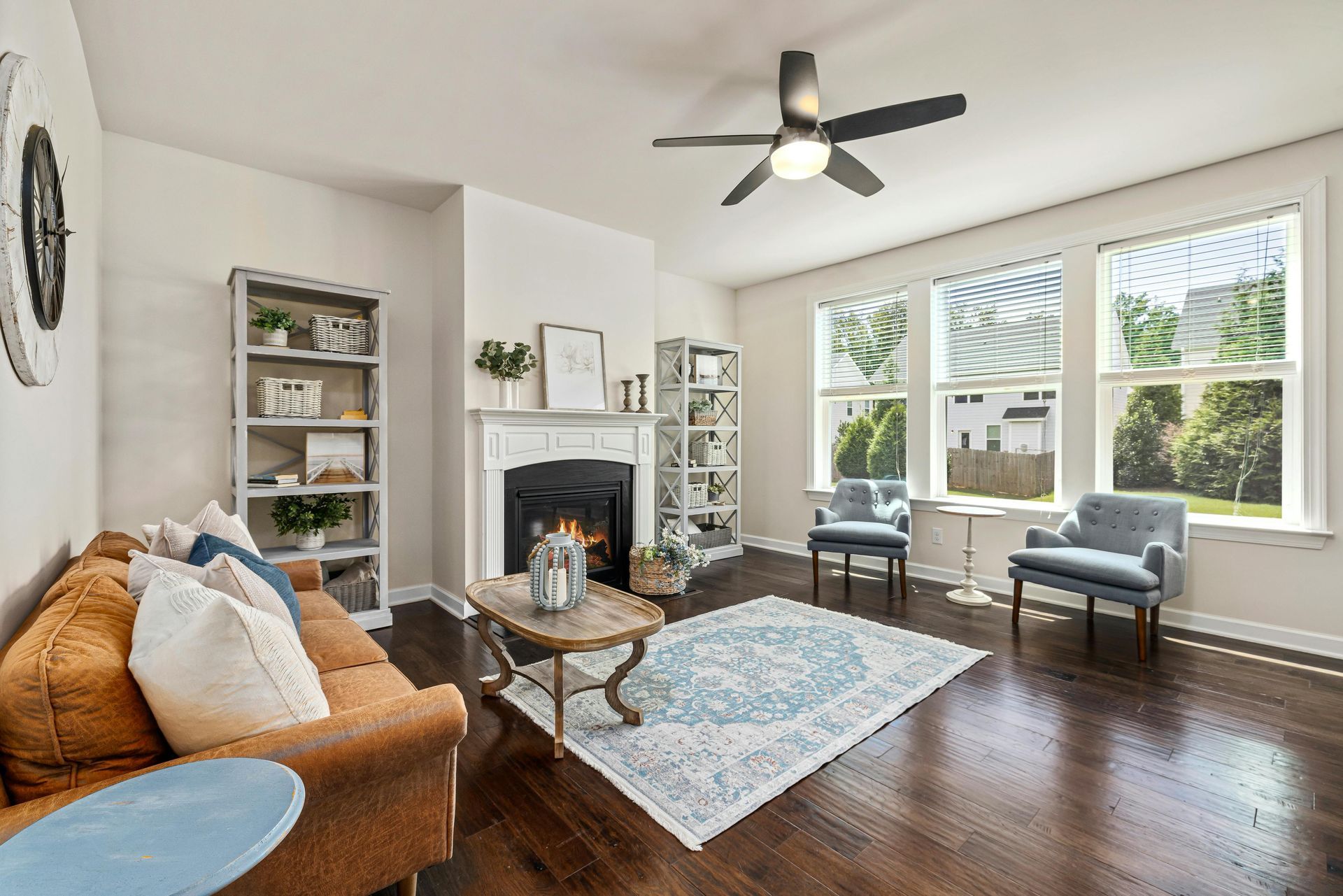 A living room with a couch , chairs , a fireplace and a ceiling fan.