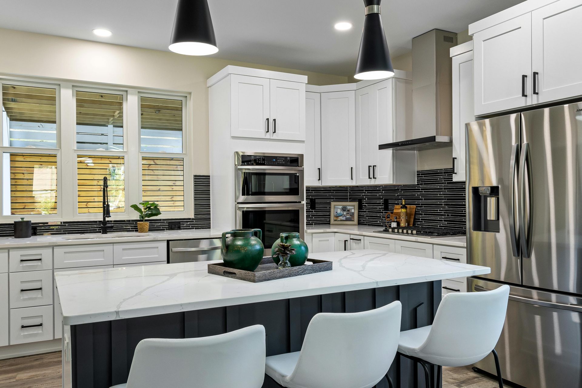 A kitchen with white cabinets , stainless steel appliances , and a large island.