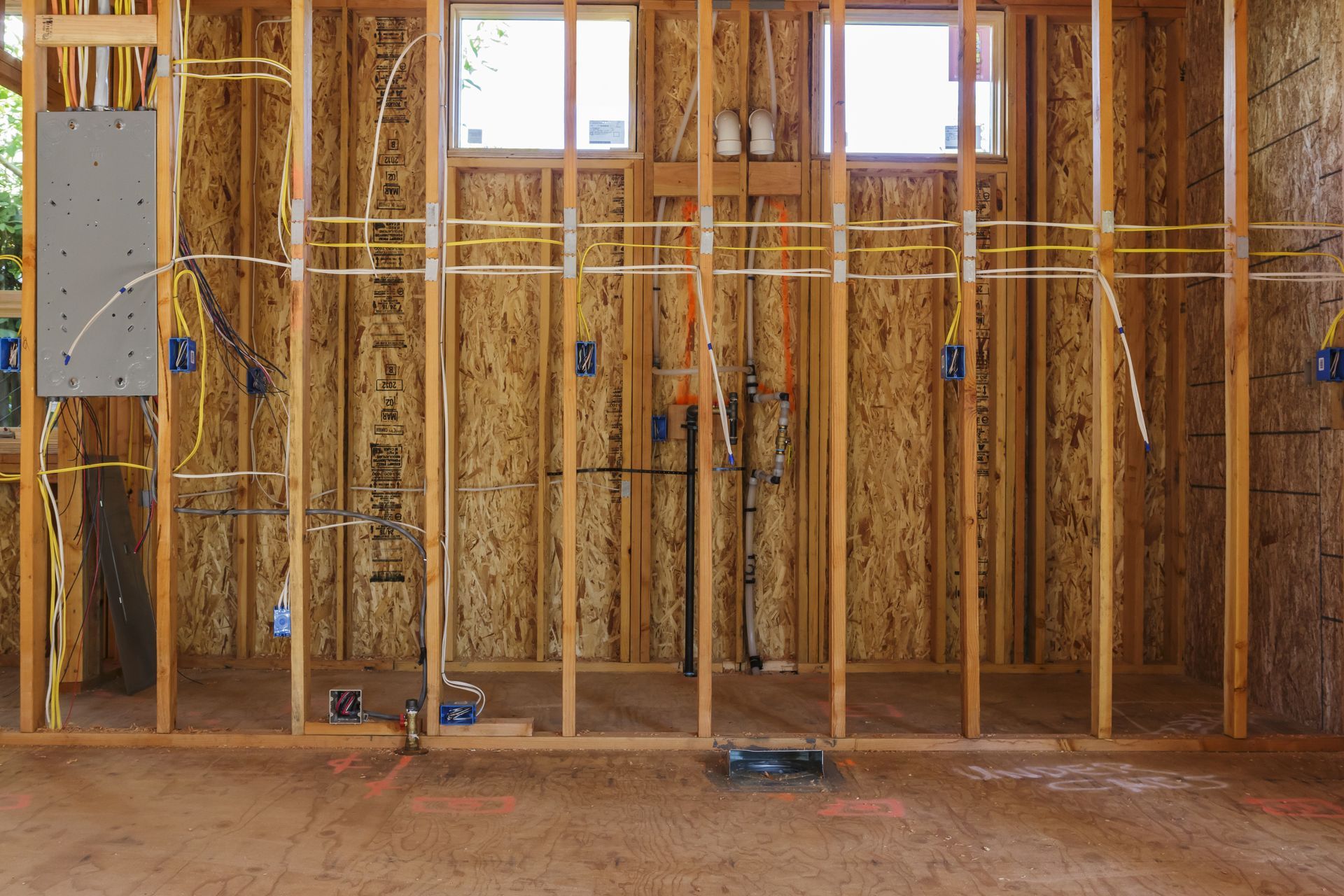 A room in a house under construction with electrical wires coming out of the walls.