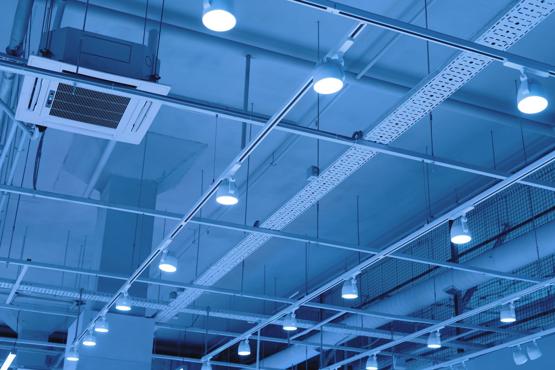 A ceiling with a lot of pipes and lights hanging from it.