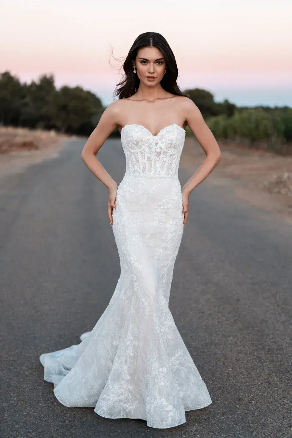 Woman in a white strapless wedding dress standing on a road.