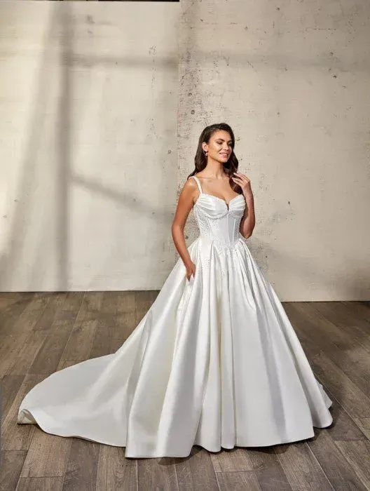 Woman in white wedding gown with pockets and train, smiling.