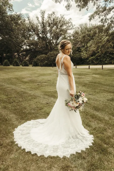 A close up of a bride in a wedding dress holding her veil.