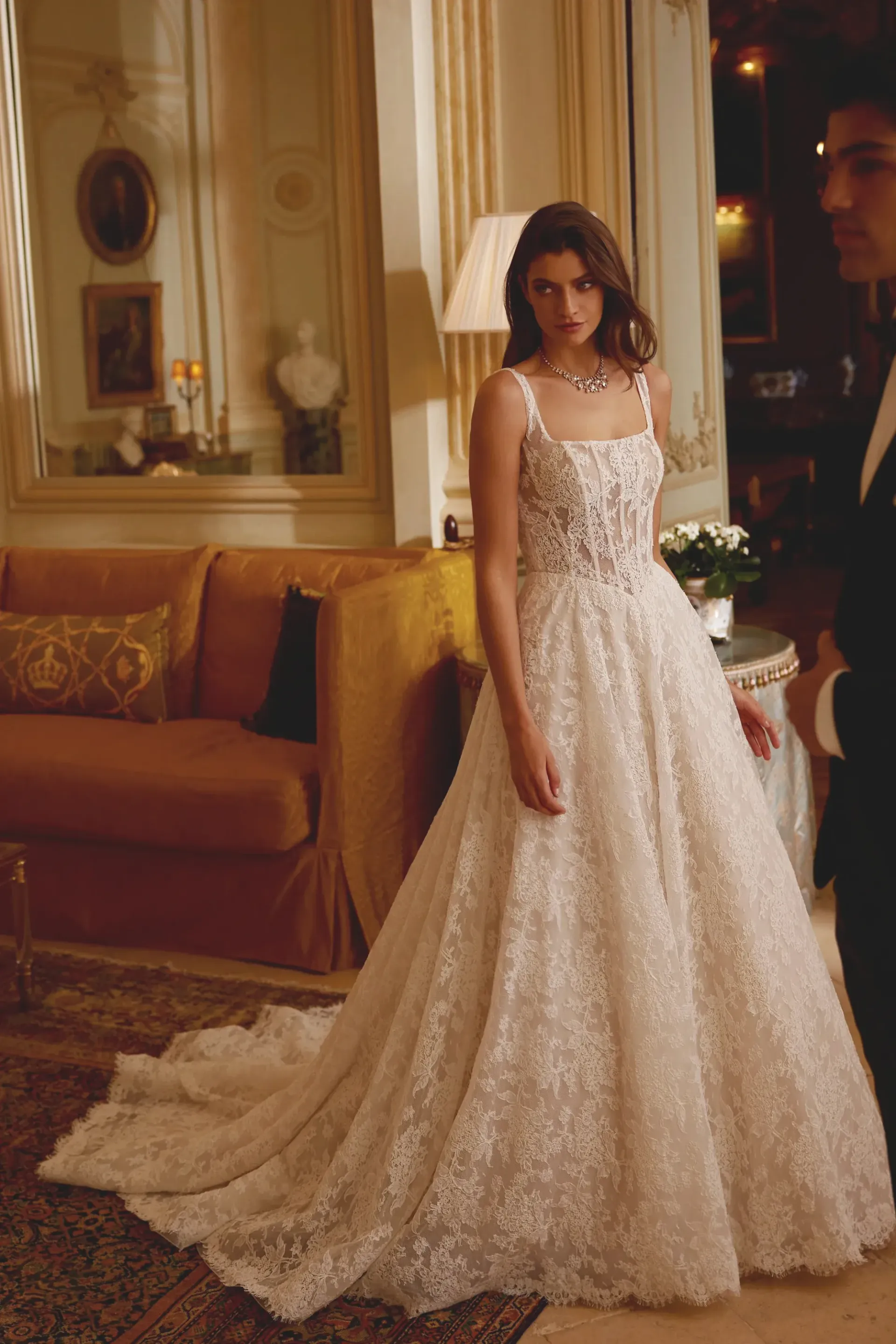 Woman in a sparkly wedding dress stands in a luxurious room with a man in a tuxedo.