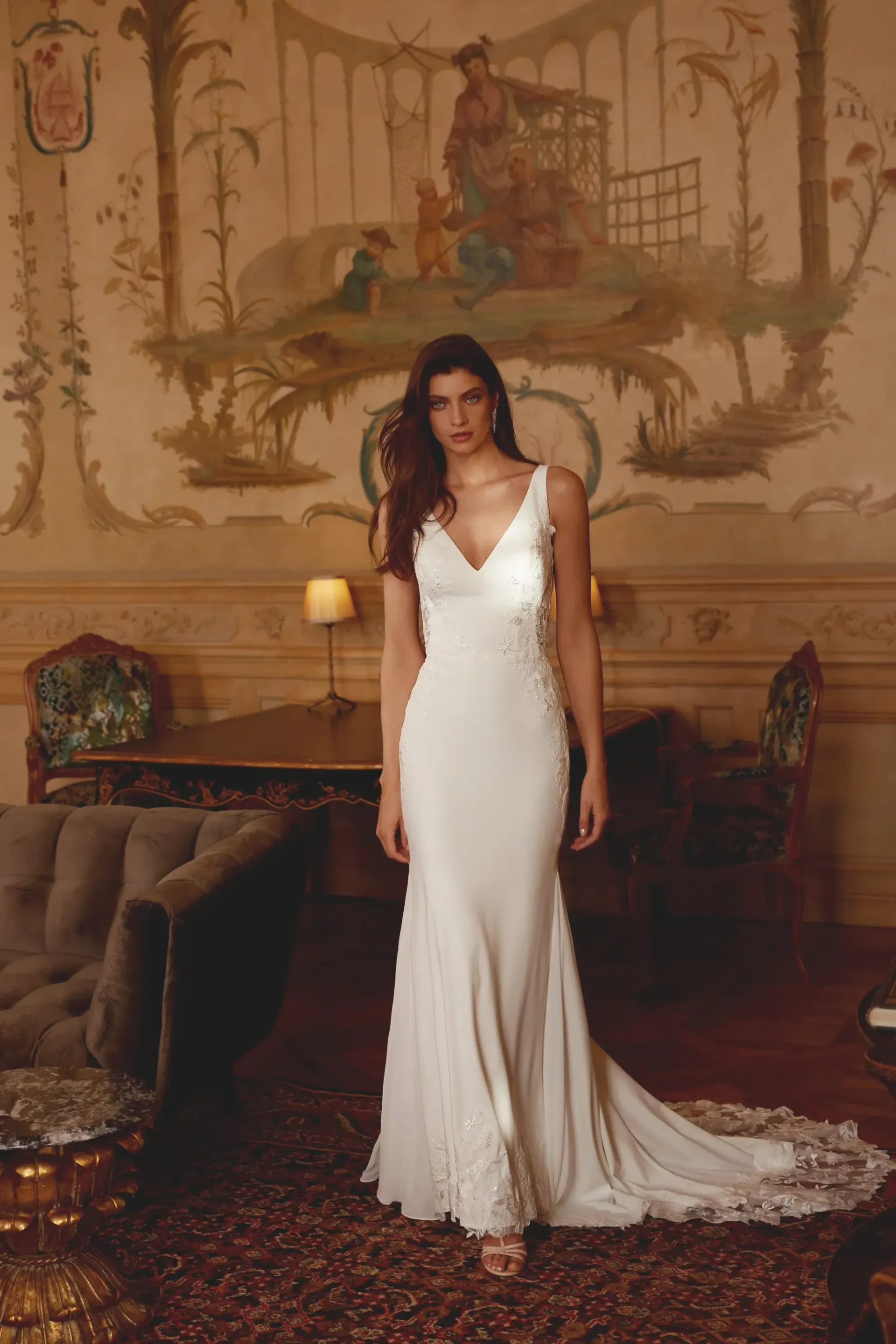 Woman in white wedding dress poses in ornate room.