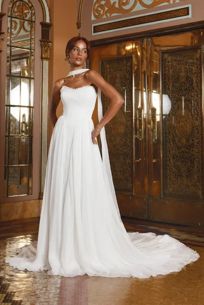 Woman in white wedding dress, posing near ornate golden doors.