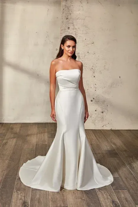 Woman in white strapless mermaid wedding dress posing in front of a textured wall.