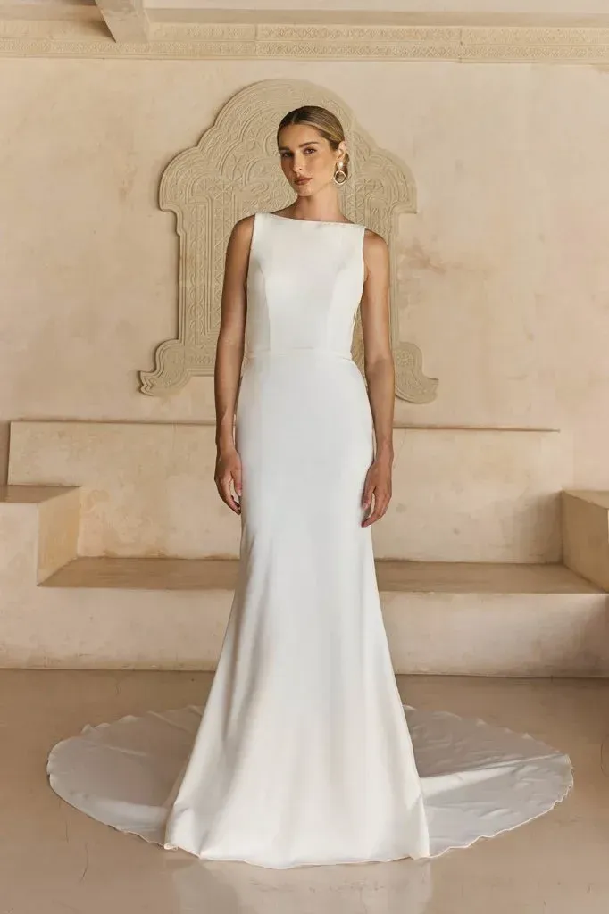 Woman in a white wedding dress, standing in front of an archway.