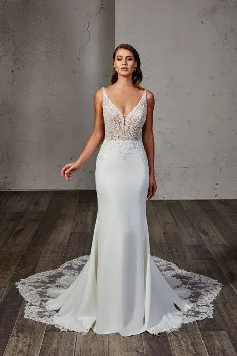 Woman in white wedding dress with lace bodice and train, in a studio.