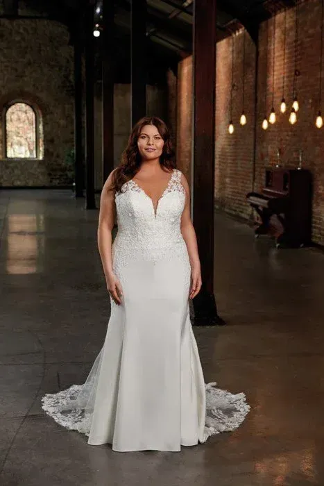 Woman in a white wedding dress, standing in an open room with a piano in the background.