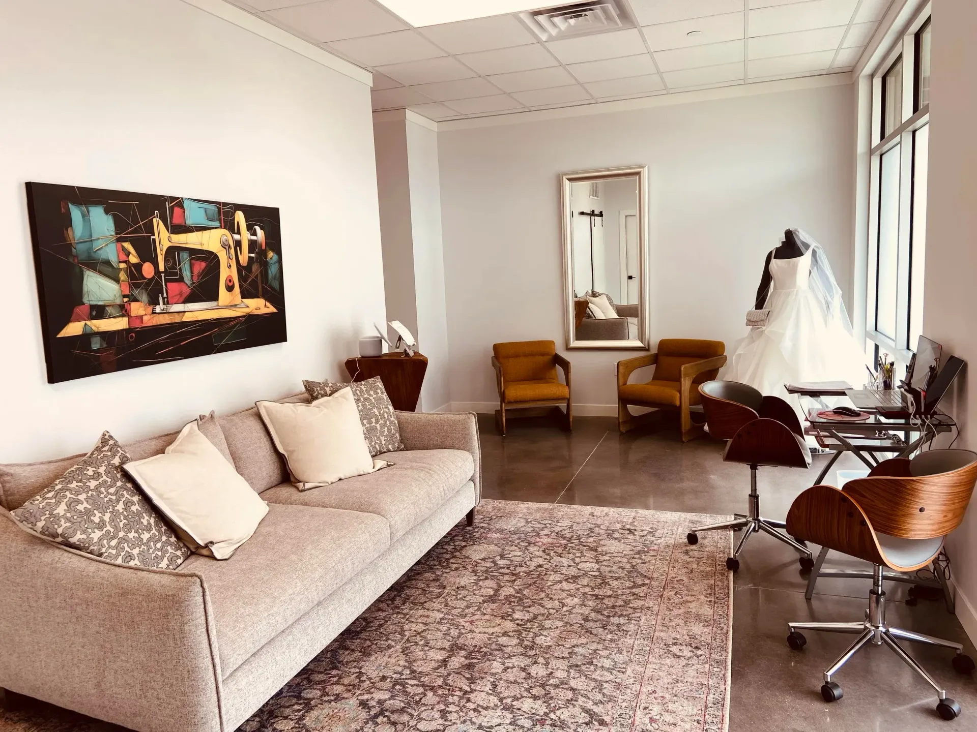 A bridal shop interior with a sofa, chairs, and a wedding dress on a mannequin.