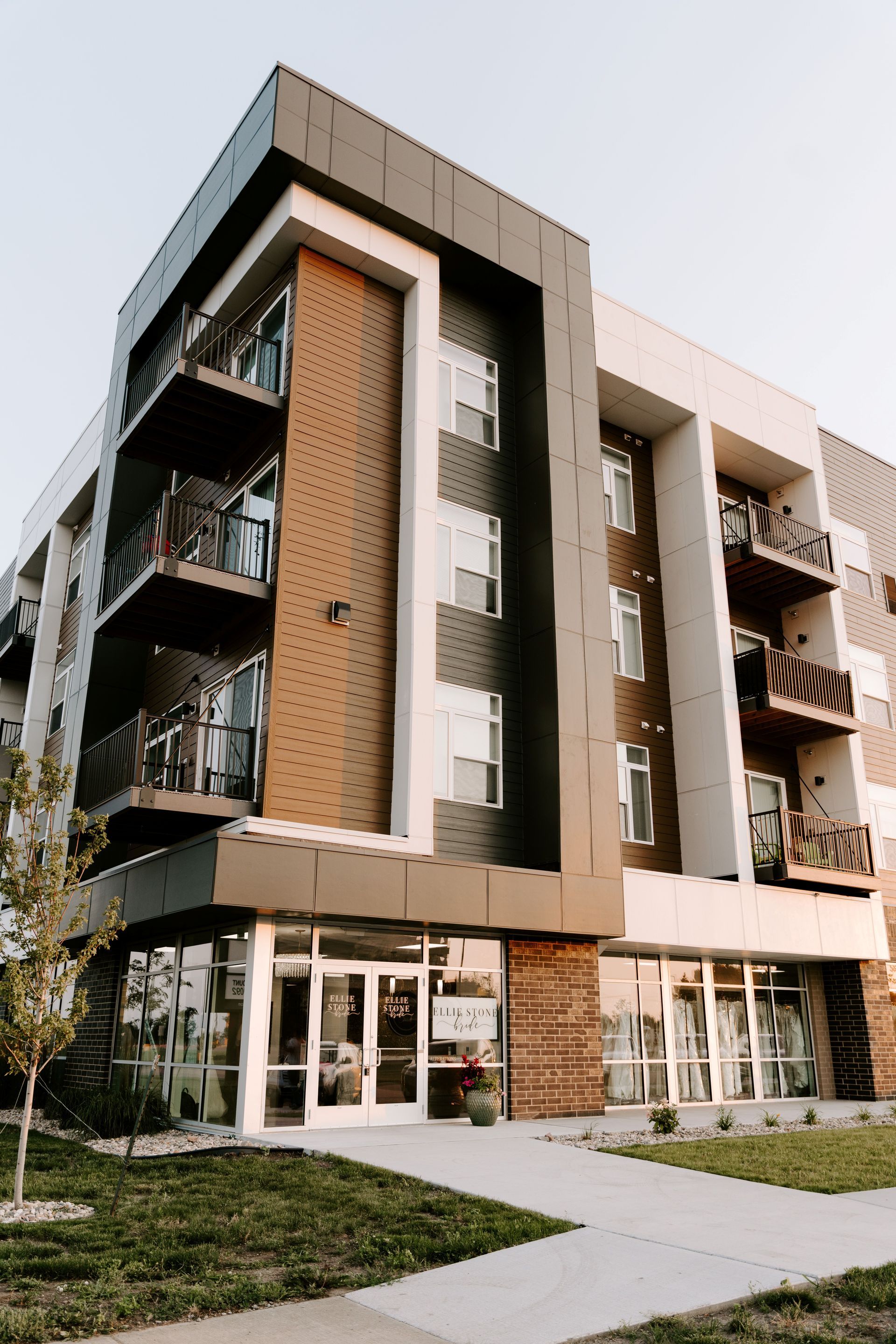 Modern multi-story apartment building with balconies, wood paneling, and glass entrance.